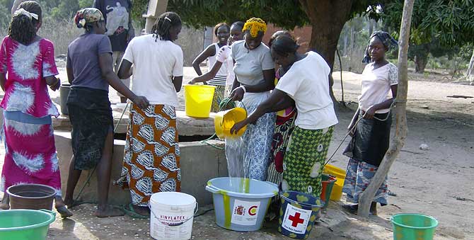 Mulheres reunidas em torno de um poço comunitário em uma vila rural